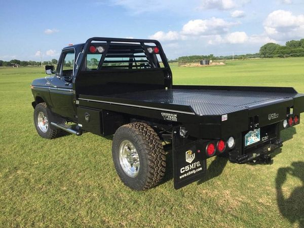 Black flatbed truck on grass field.