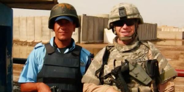 Two soldiers posing together, one in blue uniform and the other in camouflage.