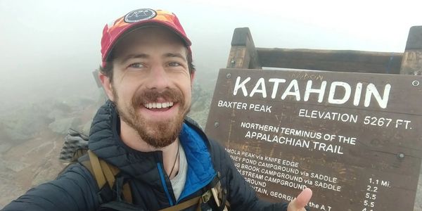 Man taking a selfie at Katahdin summit sign.