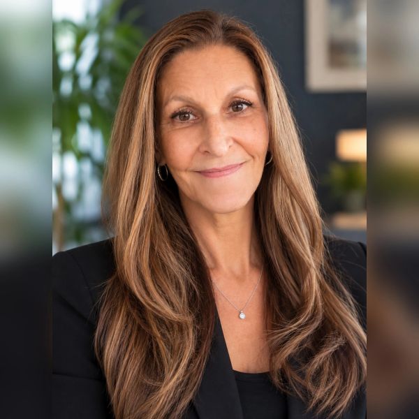 Smiling woman with long hair and black blazer.
