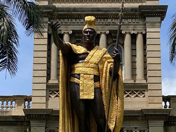 Statue of a regal figure in gold and black attire.