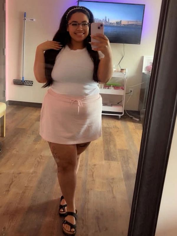 Woman taking a mirror selfie in casual outfit with glasses and long hair.