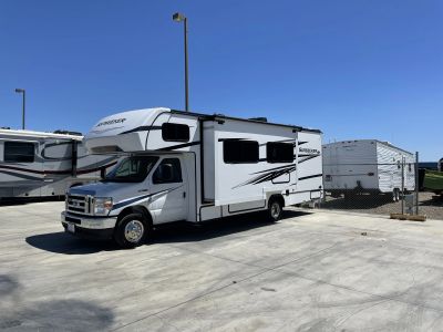 White motorhome parked on concrete under clear sky.