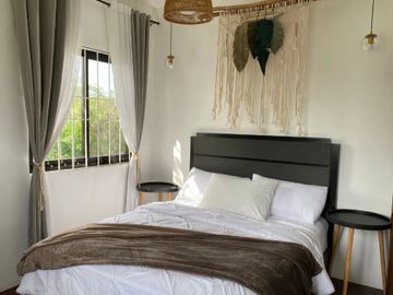 Cozy bedroom with black furniture, white bedding, and decorative wall hanging.