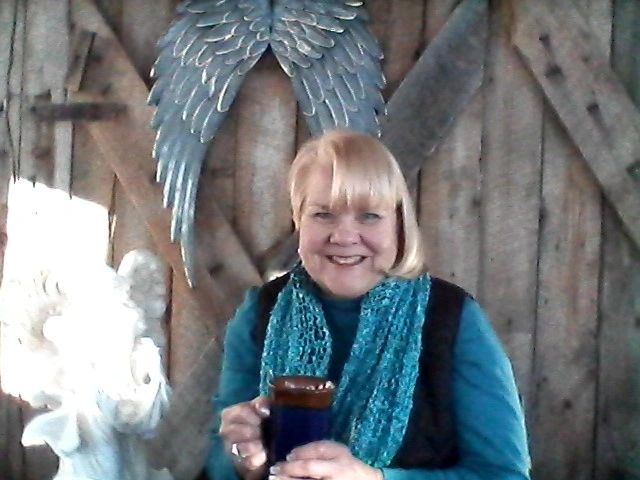 Smiling woman holding a mug with angel wings behind her.
