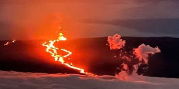 Lava flowing from an erupting volcano at night.