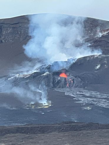 Volcanic eruption with visible lava and smoke on a mountain.