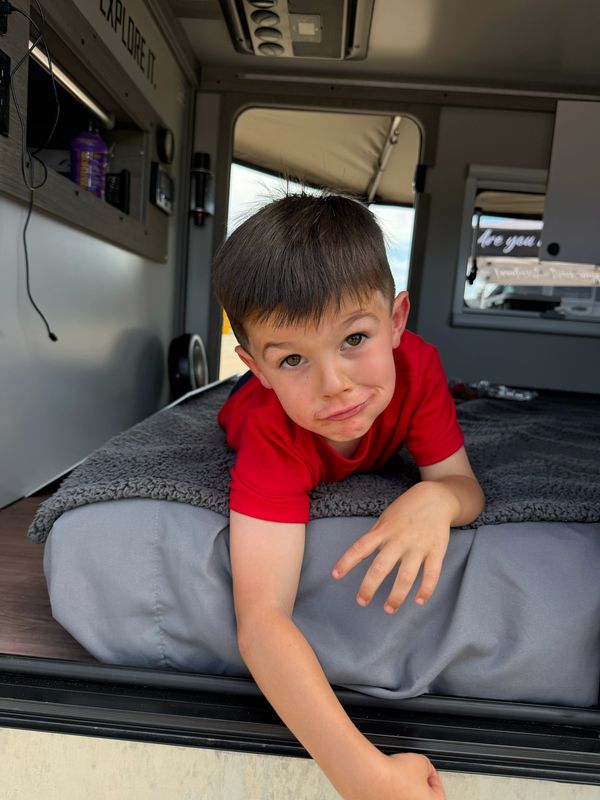 Boy making a funny face while lying on a bed.