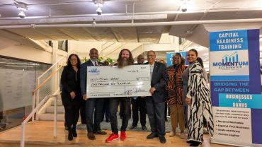 Group holding a large check at a training event.