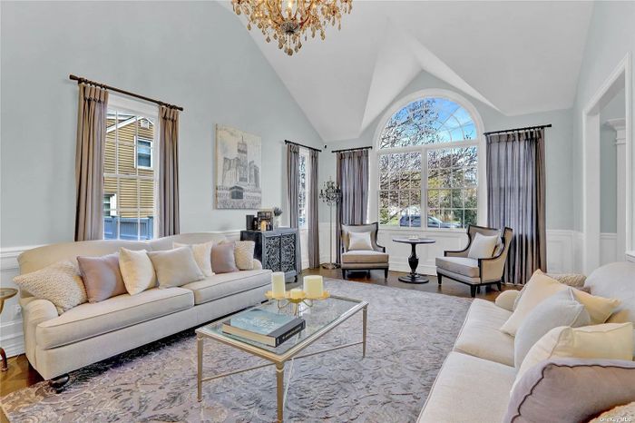 Elegant living room with neutral tones and large arched window.