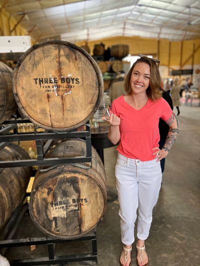 Person smiling standing next to a whiskey barrel