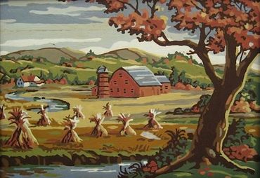 Landscape scene in the Fall with a red barn, stacks of hay and a tree in the fore-ground 