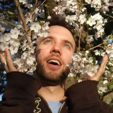 Painting instructor, male standing under a tree in bloom with white flowers