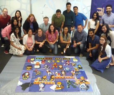 A group of people showing off the collaborative mural they made of classic video game characters