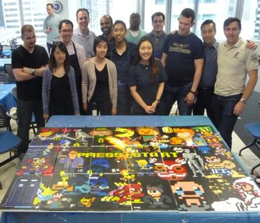 A team of people showing off their collaborative mural made up of classic video game characters