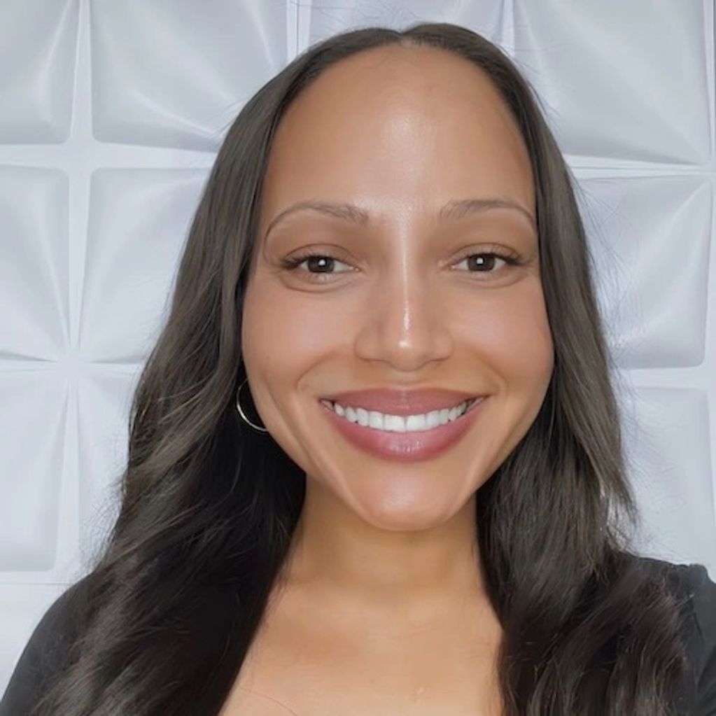 Smiling woman with long dark hair against a textured white background.