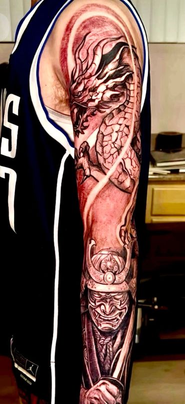 Intricate dragon and samurai tattoo sleeve on arm.