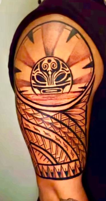 Tribal tattoo with sun and abstract patterns on upper arm.