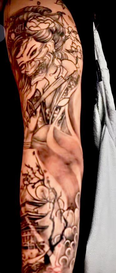Intricate tattoo sleeve featuring a fierce demon and floral motifs.