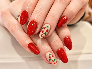 Red nails with cherry designs on two nails.