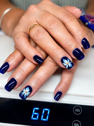 Hands with blue nails and flower nail art.