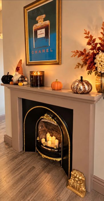 Cozy autumn fireplace with candles and decorative pumpkins.