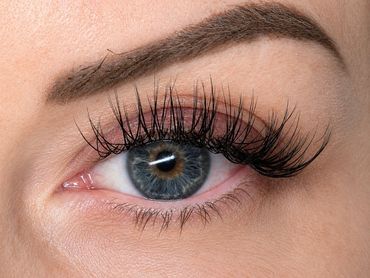 Close-up of an eye with long eyelashes and styled eyebrow.