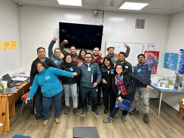 Group of smiling coworkers posing happily in an office room.