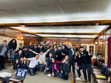 Group of people posing happily in a wood-paneled room.