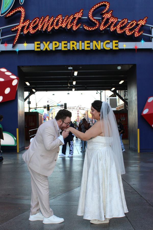 Bride and groom share a romantic moment under Fremont Street Experience sign.