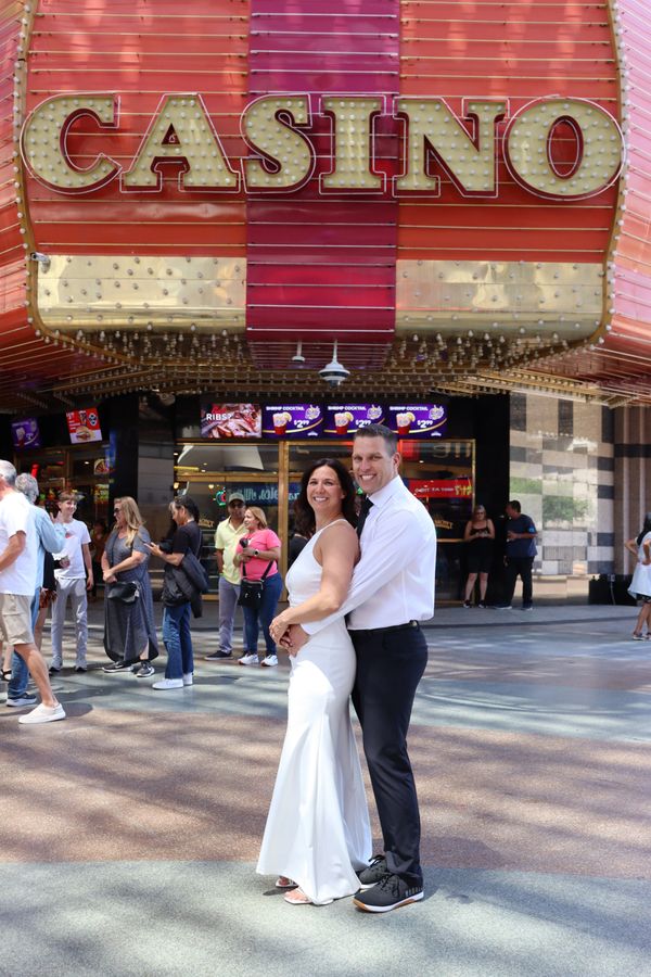 Couple in formal attire posing happily outside a casino.