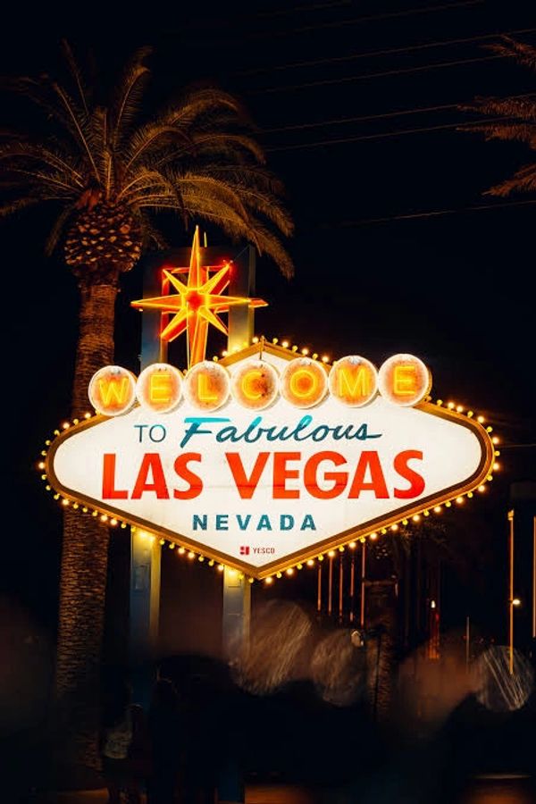 Illuminated Welcome to Fabulous Las Vegas sign at night with palm trees.