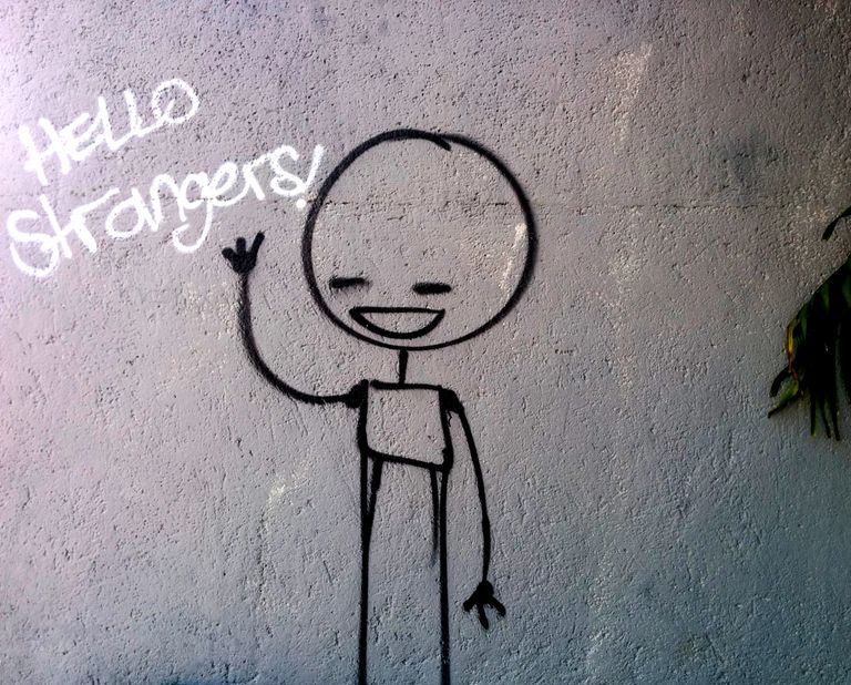 Graffiti of stick man waving and text saying 'Hello strangers!'