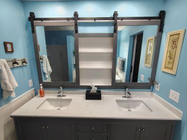 Double sink bathroom vanity with sliding barn door mirror.