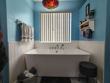Bathtub under window with blue walls and towels.