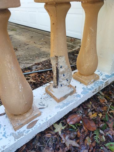 Damaged beige concrete baluster with exposed rebar and screws.