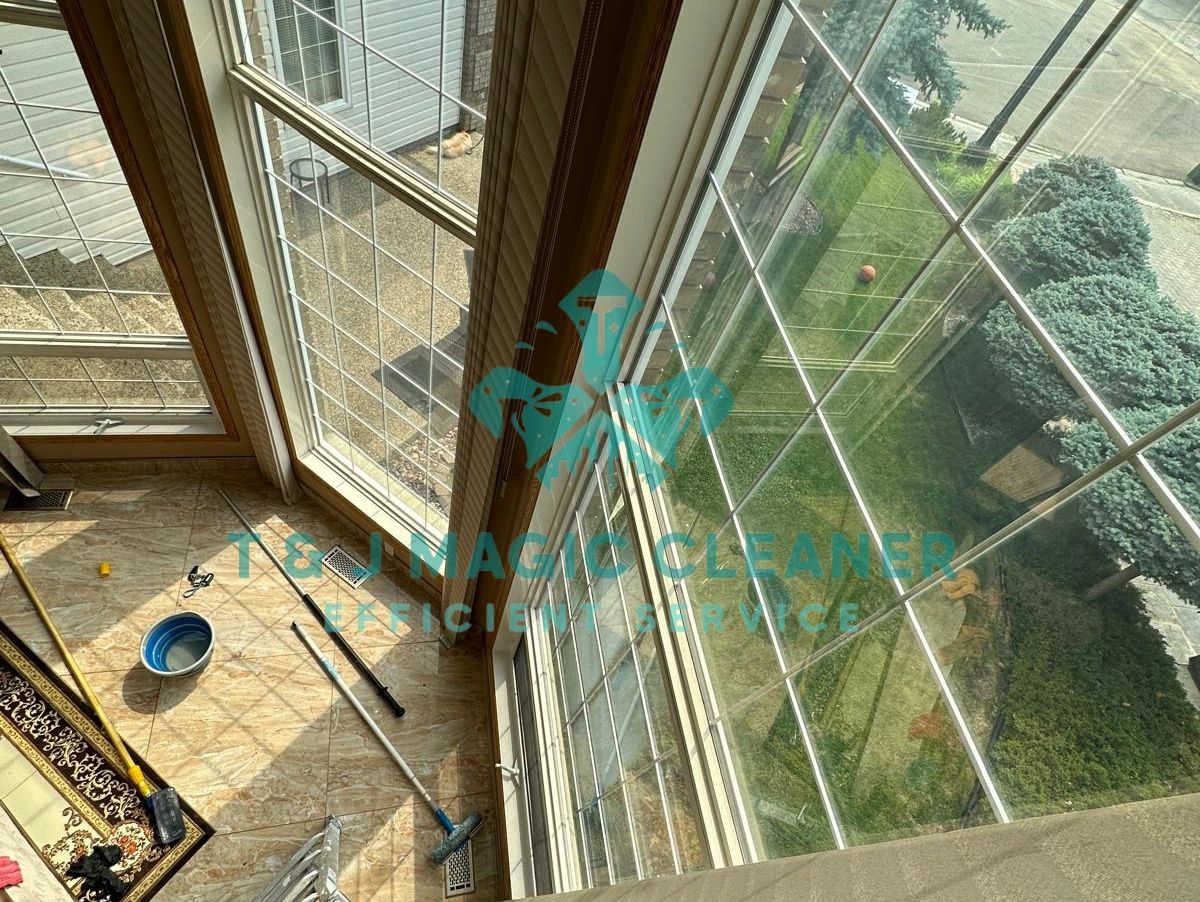 Cleaning tools and ladder near large grid windows in a living room.