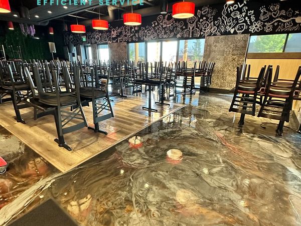 A clean, modern dining area with shiny, polished floors and red hanging lamps.