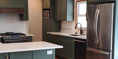 Kitchen with dark green cabinets and new appliances after remodel