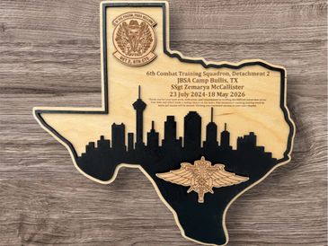 Wooden plaque shaped like Texas with San Antonio skyline and military insignia.