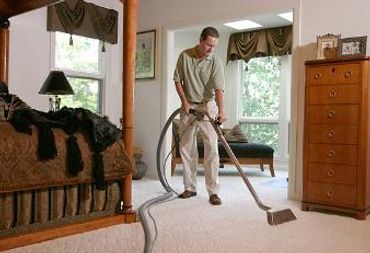 A man cleaning the floor of a house with machine