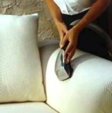 A man sitting and cleaning a sofa in white color