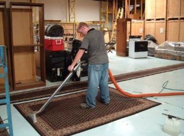 A man cleaning a mat on the floor with a machine