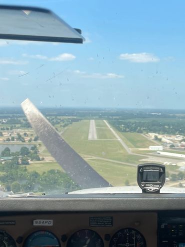 View from a small airplane cockpit approaching a runway on a clear day.