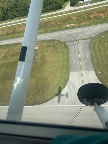 Shadow of a small airplane on a taxiway from inside the cockpit.