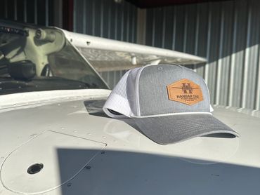 Gray and white mesh cap with 'Hangar One' logo on an airplane wing.