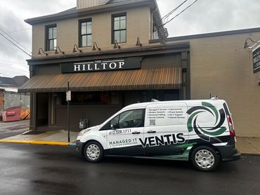 A Ventis service van parked outside The Hilltop building on a rainy day.