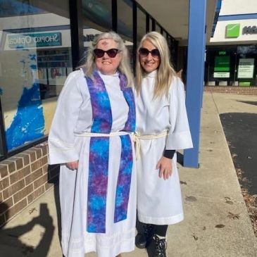 Two women in white robes standing outside a building.