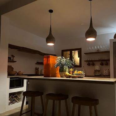 Cozy kitchen island illuminated by pendant lights with flowers and fruit on top.