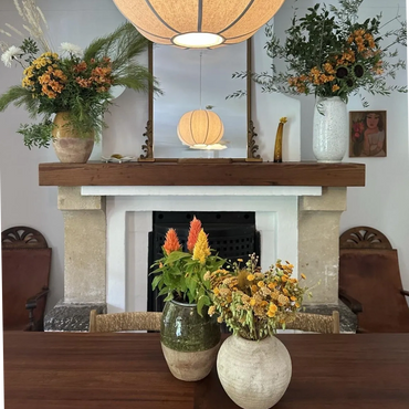 Cozy interior with floral arrangements, a wooden table, and a glowing pendant lamp.